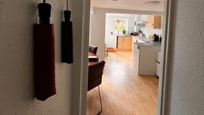 A hallway leading to a kitchen with wooden flooring and white cabinets. - Central Bridport, a cosy pet-friendly cottage. (Bridport)