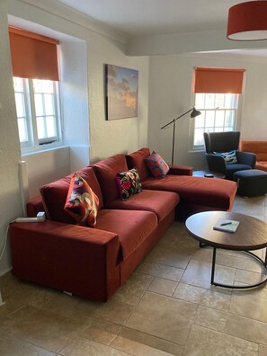 Ein modernes Wohnzimmer mit einer Eckcouch, einem runden Couchtisch und einer Stehlampe.