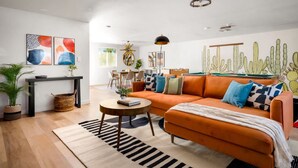 A modern living room with a sofa, coffee table, and artwork on the walls. - Chic Home With Backyard Oasis Pool Game Room (Phoenix)