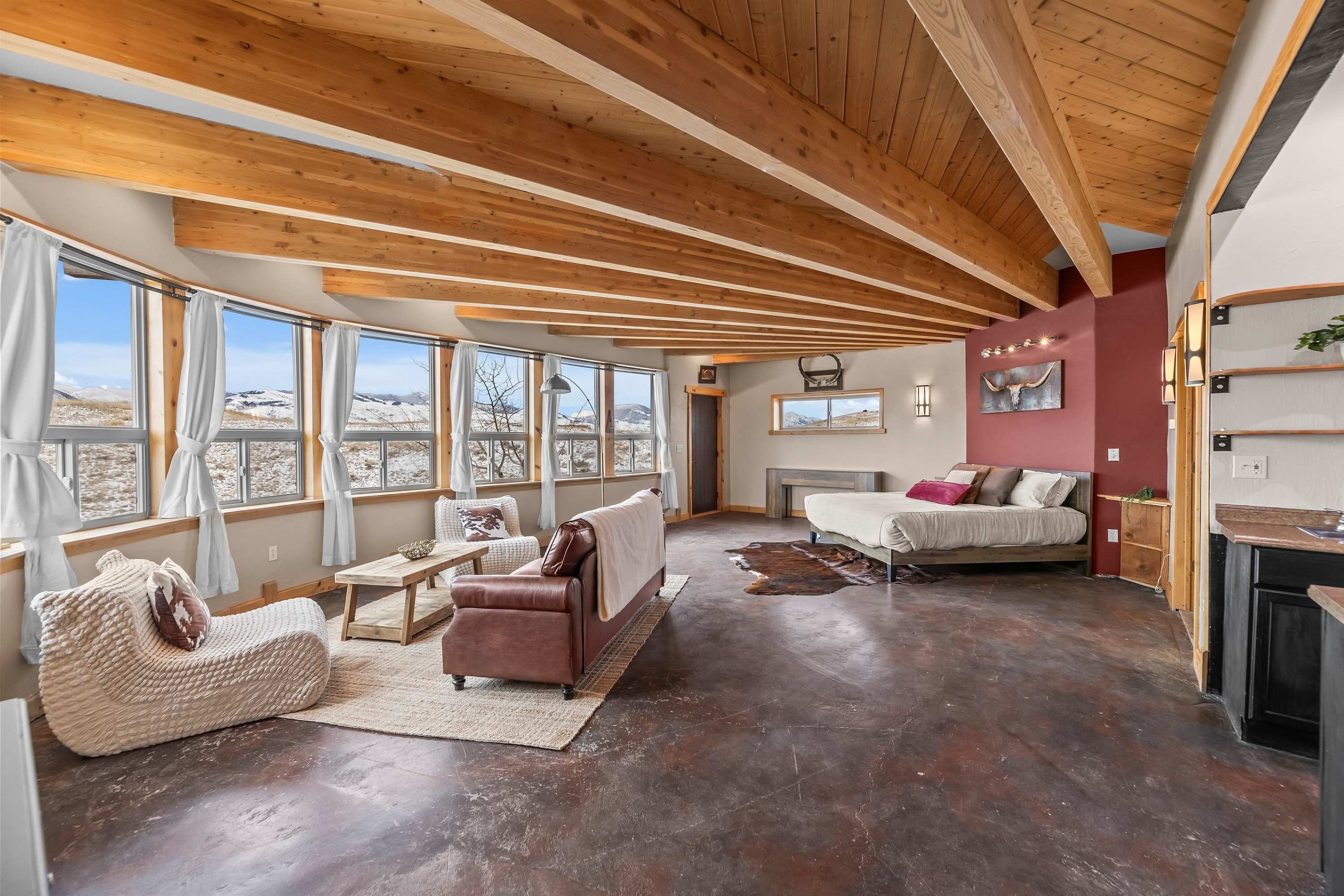 A spacious living room with a high ceiling, large windows, and a fireplace.