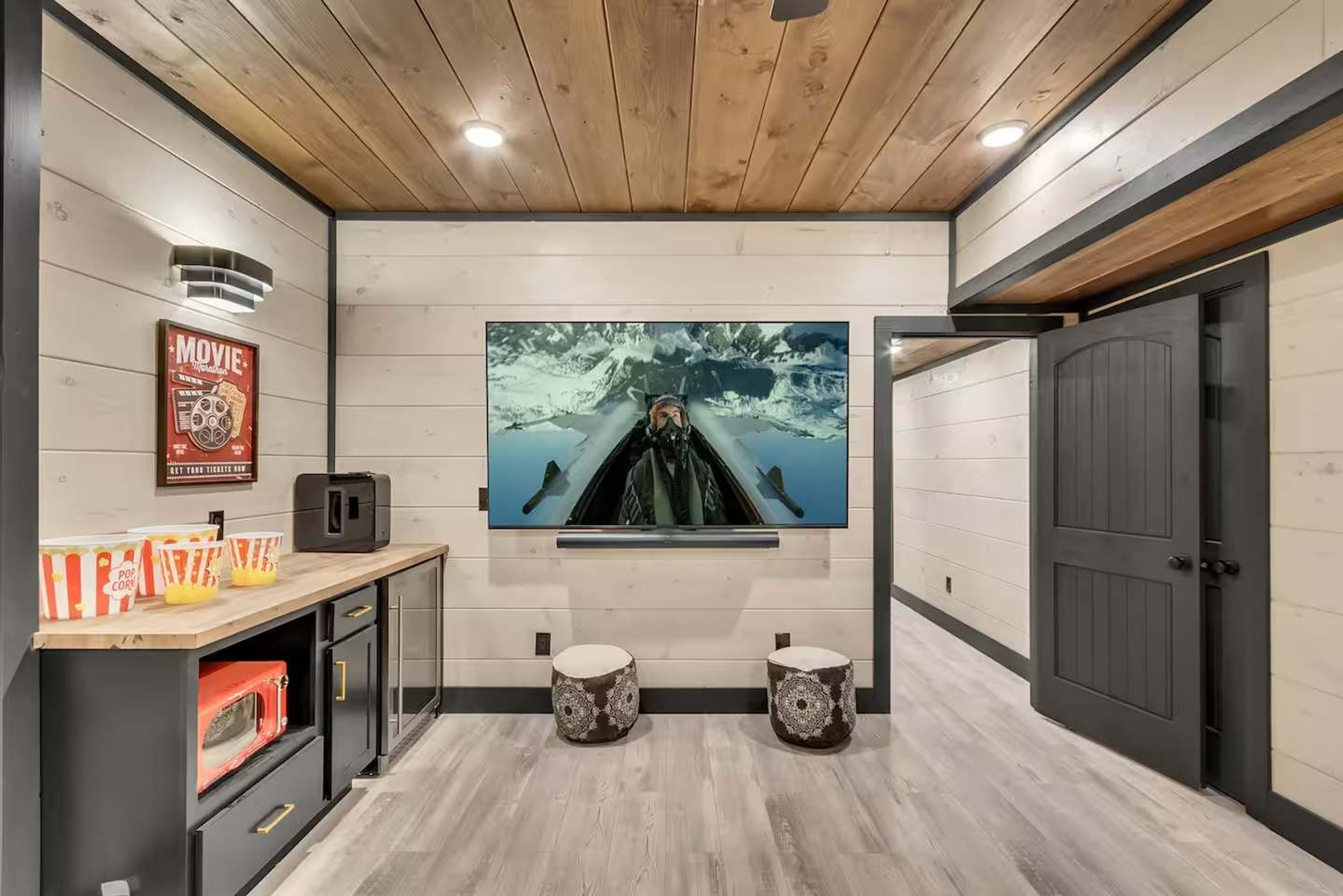 A modern interior with a mounted TV, popcorn containers, and a wooden ceiling.