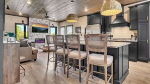 Una cocina moderna con armarios oscuros, una isla central y un comedor con sillas de mimbre.