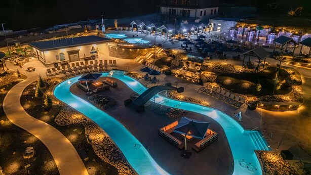 Un resort con una amplia piscina, zonas de estar al aire libre y un patio bien iluminado.