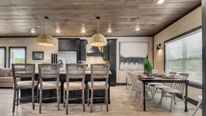 Una cocina moderna con techo de madera, armarios oscuros y una isla central con sillas.