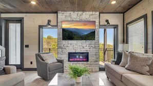 Una sala de estar moderna con chimenea de piedra, asientos cómodos y amplios ventanales con vistas panorámicas.