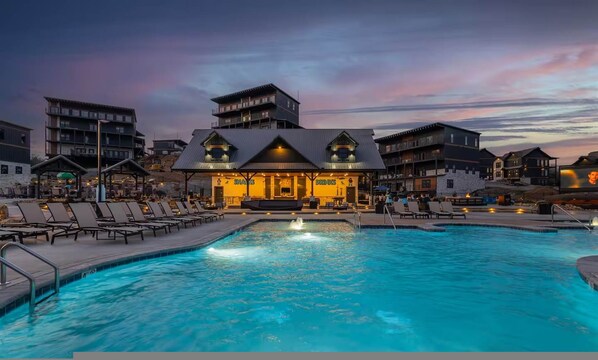 A pool area with lounge chairs and a bar in the background. - Firefly Lodge Indoor Pool Theater Hot Tub (Sevierville)
