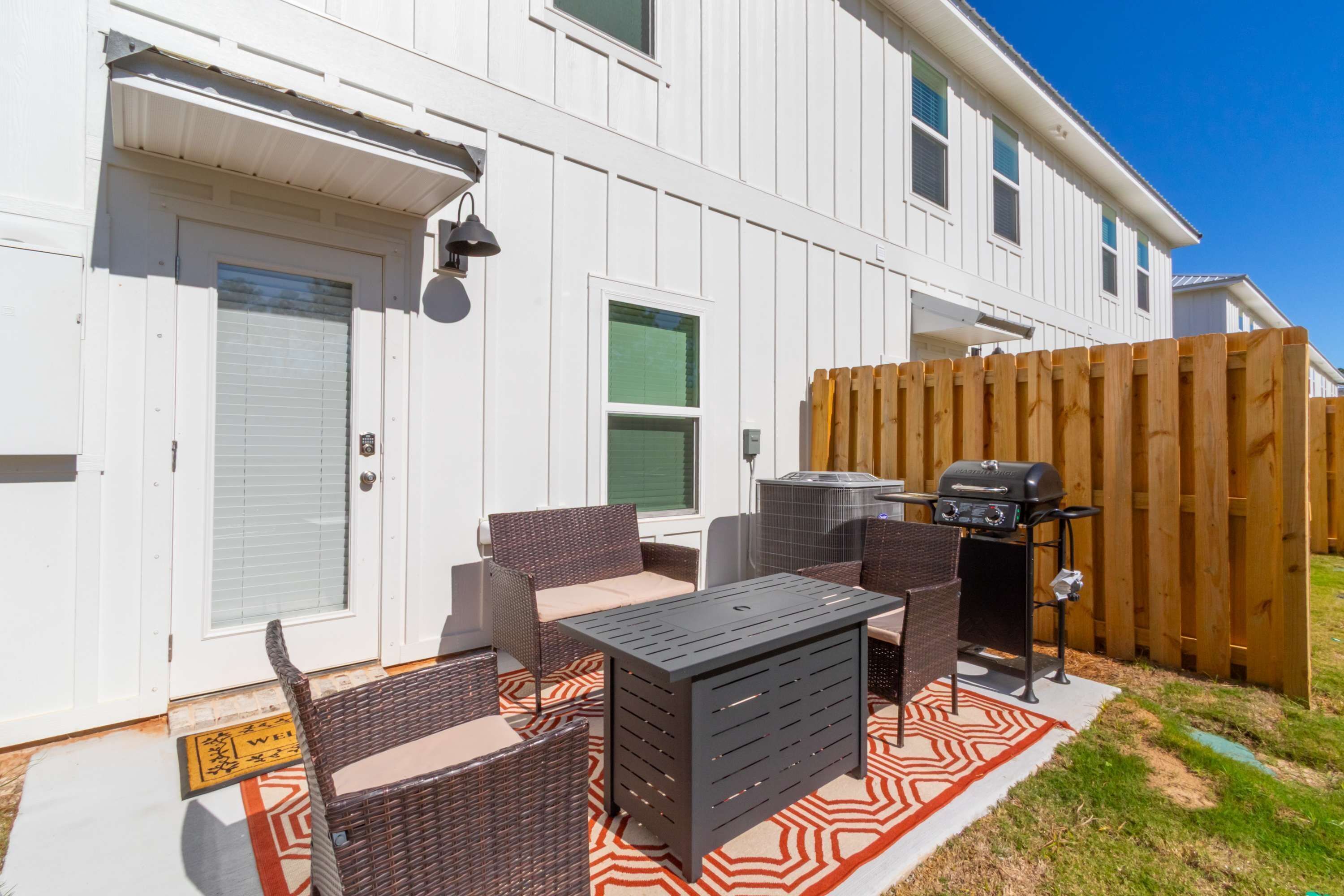 A patio with wicker furniture, a grill, and a door with a window.