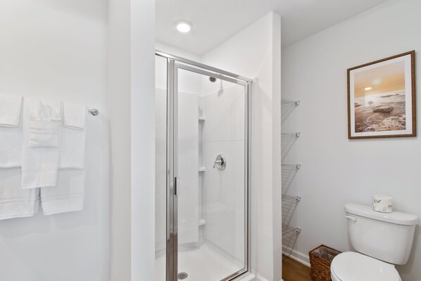 A modern bathroom with a glass shower enclosure, white fixtures, and a framed picture on the wall. - New Sleeps 7 Beach Fun Dining Palmaway (Orange Beach)