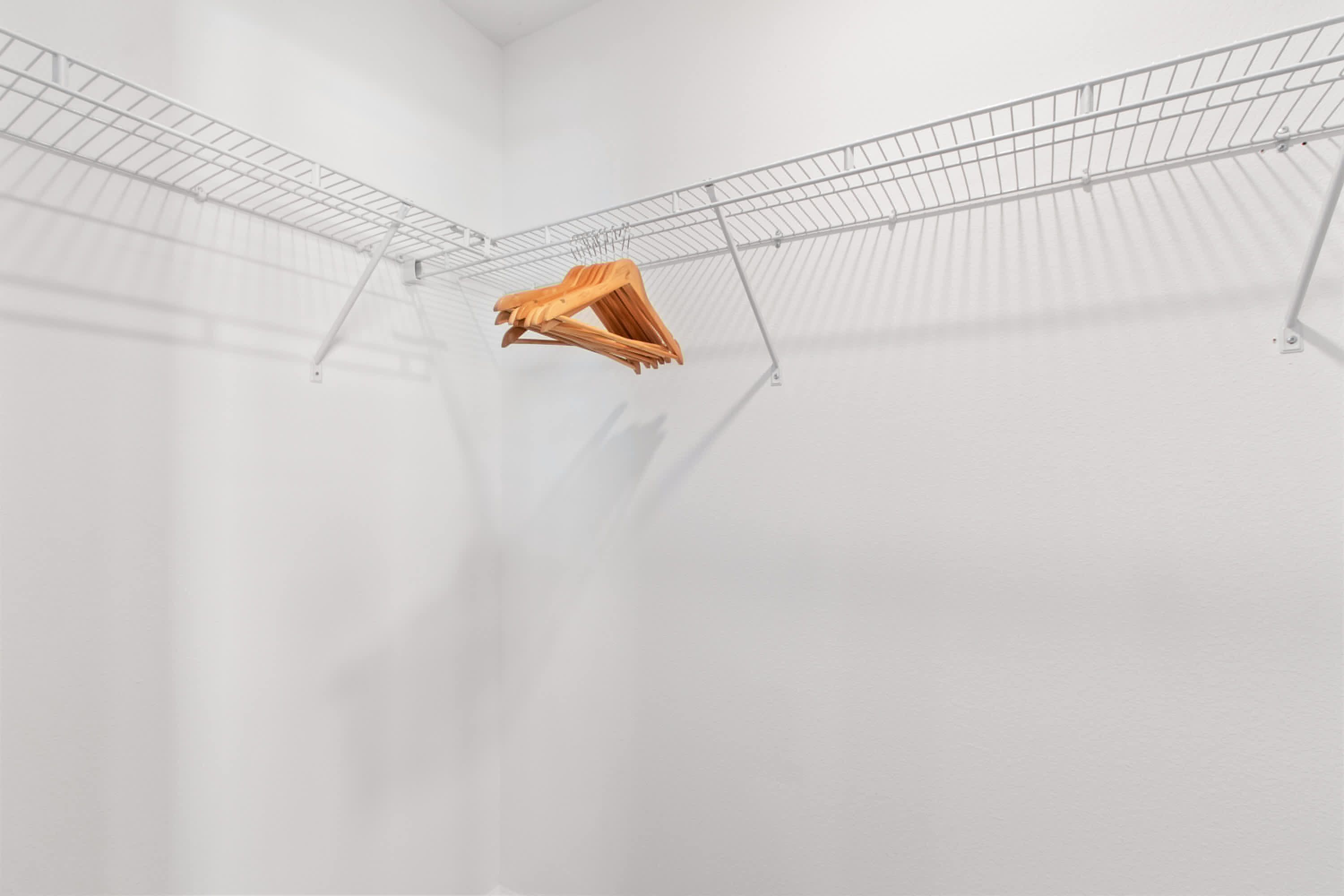 Una habitación con paredes blancas, un techo de paneles metálicos y un perchero de madera colgando.