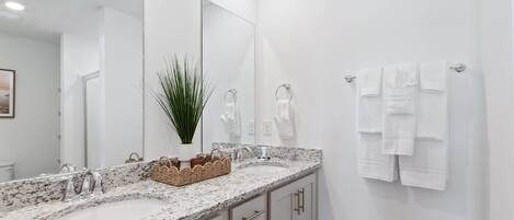 A bathroom with two sinks, a large mirror, and a towel rack.