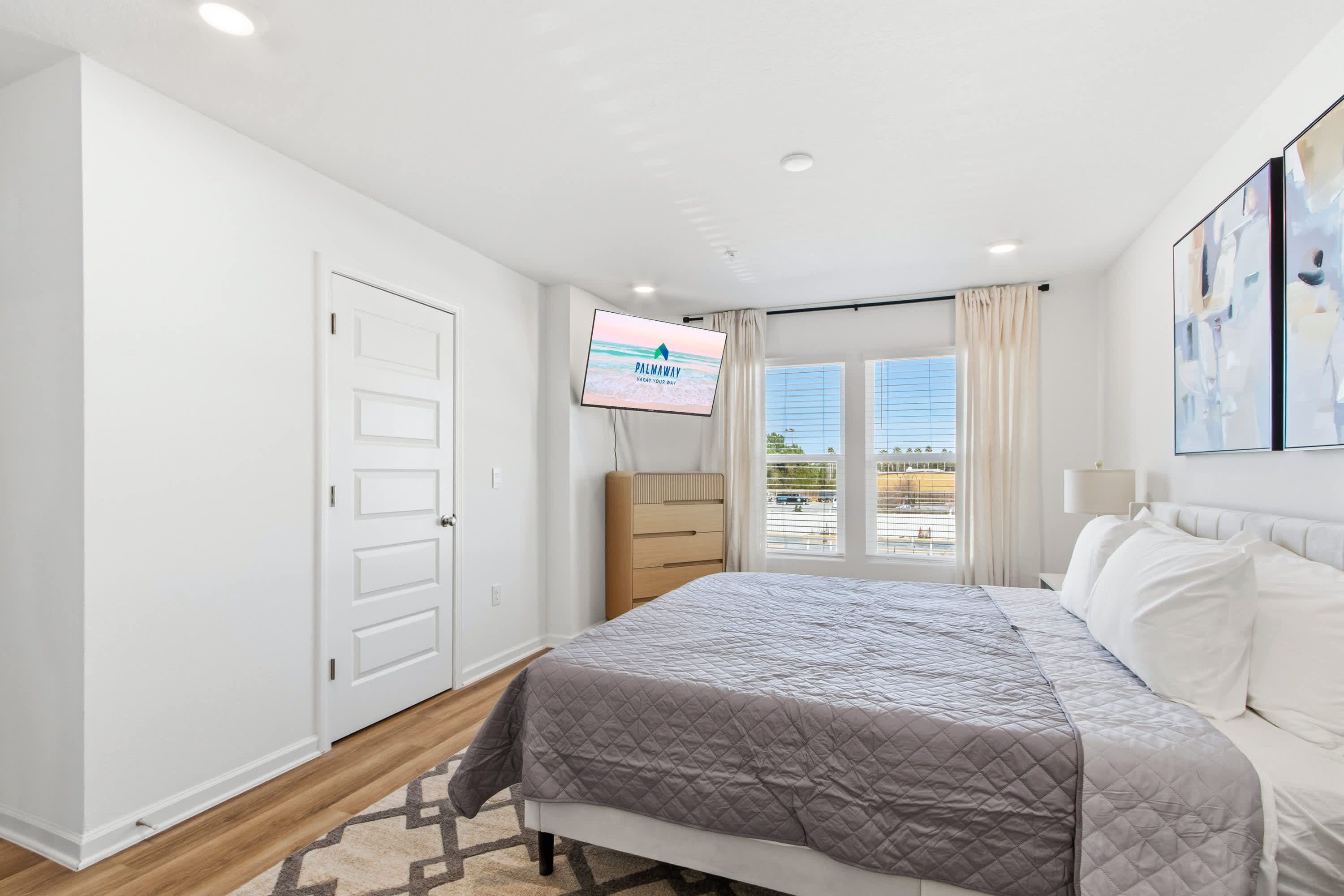 Een slaapkamer met een bed, een televisie, een raam met gordijnen en uitzicht op de omgeving.
