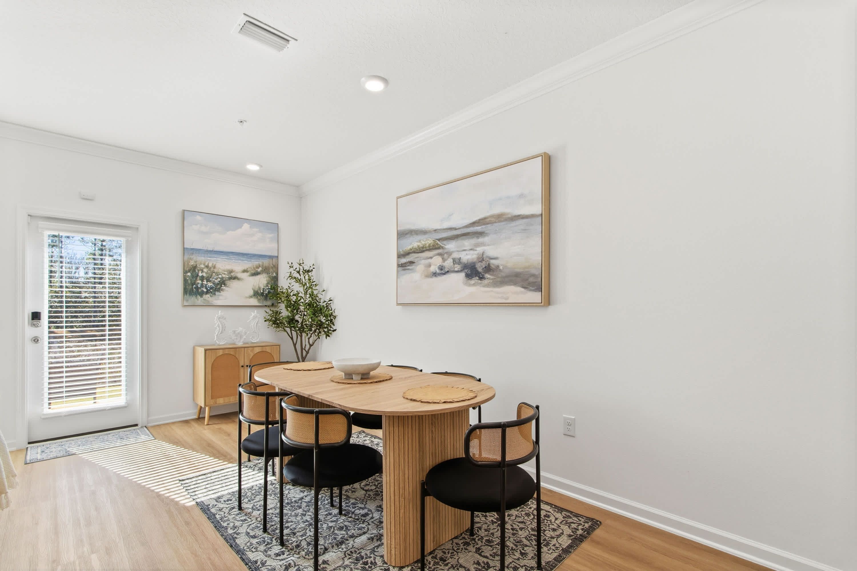 A dining area with a wooden table, black chairs, and a blue patterned rug.