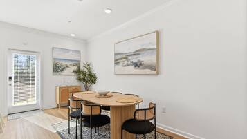 A dining area with a wooden table, black chairs, and a blue patterned rug.