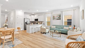 A modern living room with a sofa, coffee table, and dining area. - NEW Sleeps 7 Beach Fun Dining Palmaway (Orange Beach)