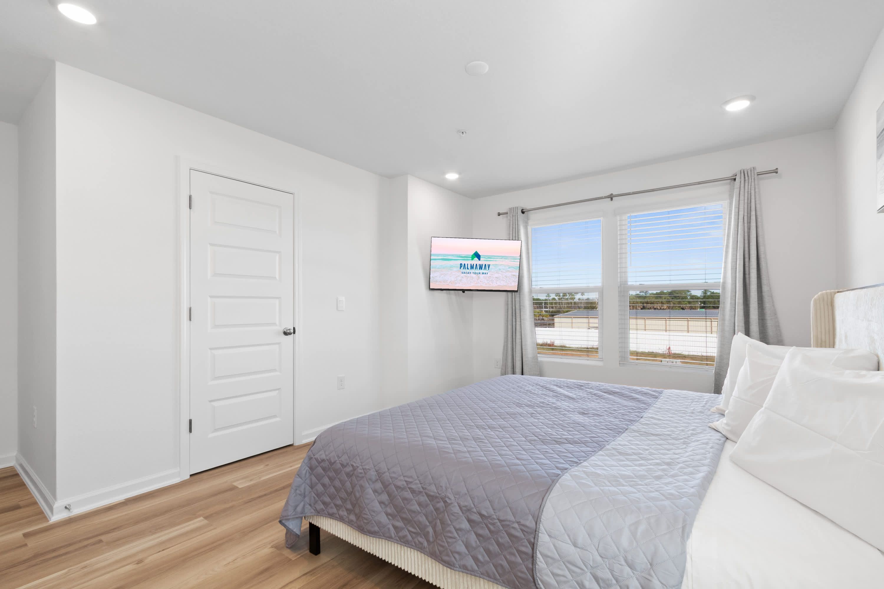 Un dormitorio con cama, televisión, ventana con vistas y puerta.