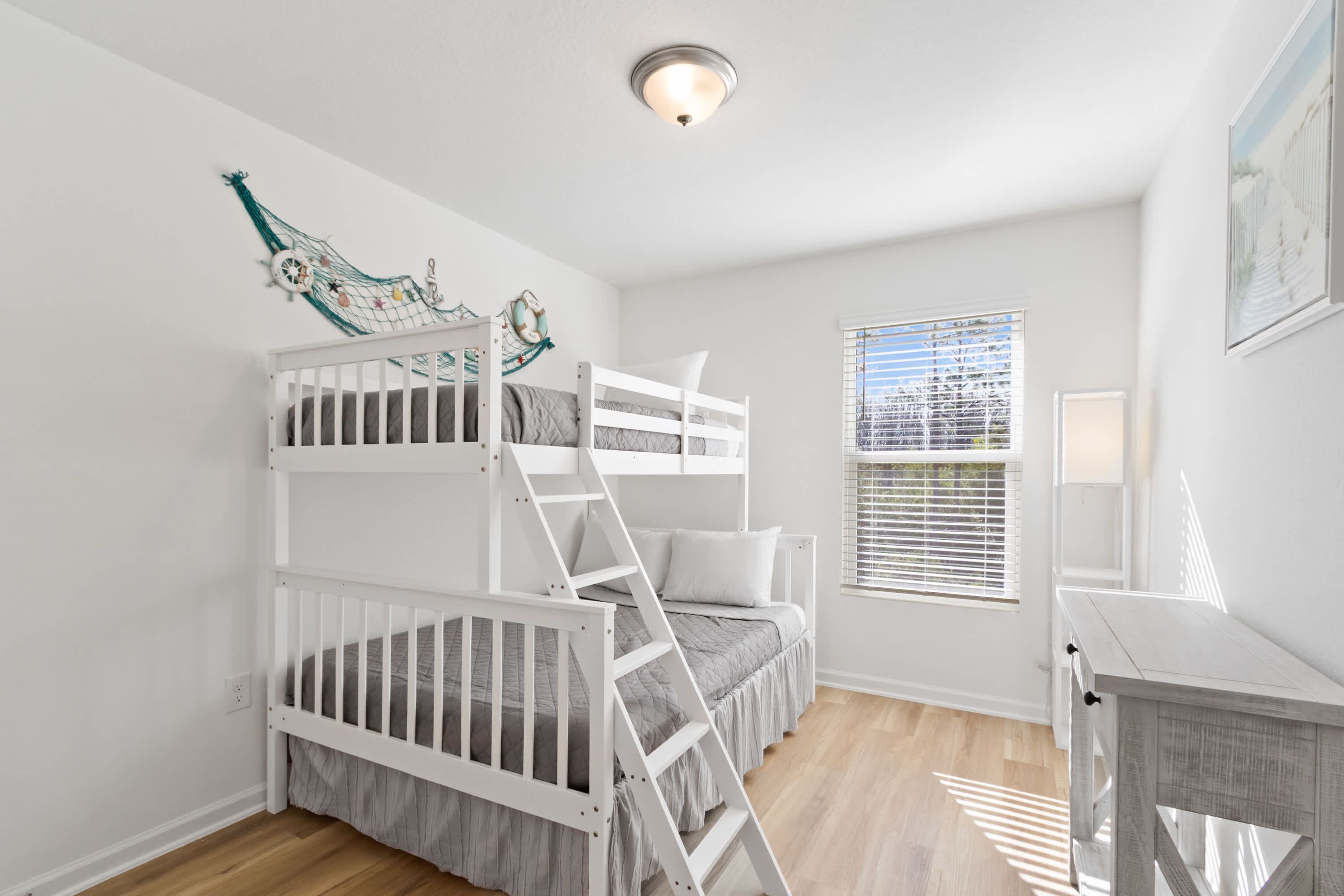 A room with a bunk bed, a desk, and a window with blinds.
