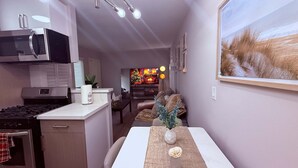 Eine moderne Küche mit Mikrowelle, Herd und Schränken. Es gibt einen Essbereich mit Tisch und Stühlen sowie ein Wohnzimmer mit Fernseher und Kamin.