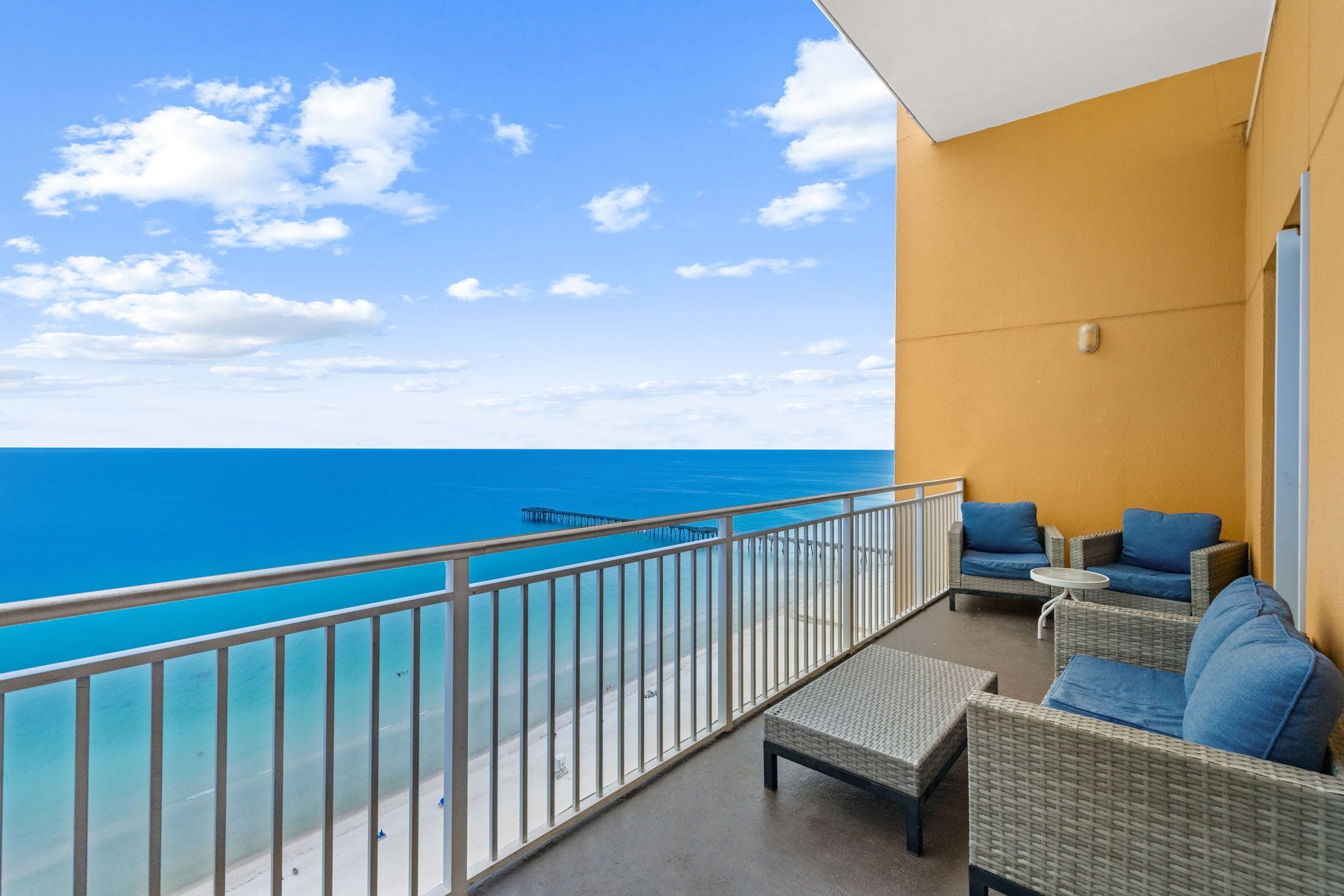 Un balcon avec vue sur la mer, aménagé avec des meubles et des coussins en osier.