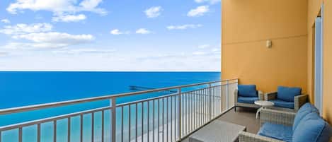 Un balcon avec vue sur la mer, aménagé avec des meubles et des coussins en osier.