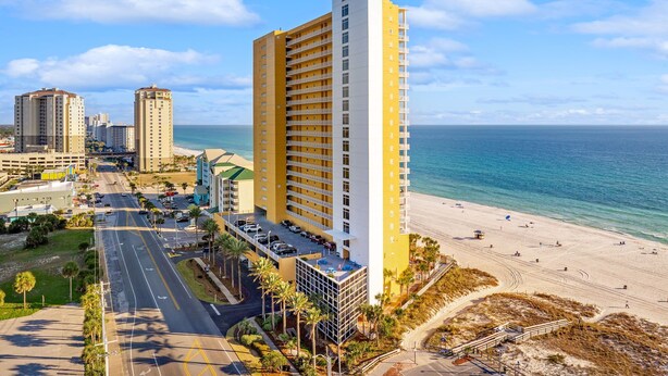 Ein Hochhaus-Hotel mit Blick auf den Strand, mehreren Etagen und einem Parkplatz.