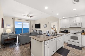 A modern kitchen with white cabinets, a granite countertop, and stainless steel appliances. - New UNIT, Penthouse with gulf views close to pier park! (Panama City Beach)
