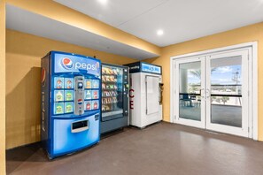 A vending area with Pepsi and ice vending machines, a glass door leading to an outdoor seating area. - New UNIT, Penthouse with gulf views close to pier park! (Panama City Beach)