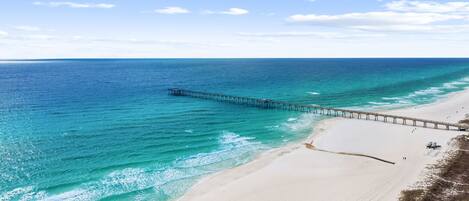 A beach with a pier extending into the ocean.