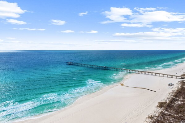 A beach with a pier extending into the ocean. - New UNIT, Penthouse with gulf views close to pier park! (Panama City Beach)