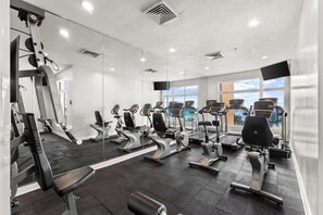 A gym with exercise equipment, large windows, and a mirror wall. - New UNIT, Penthouse with gulf views close to pier park! (Panama City Beach)