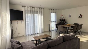 A modern living room with a sofa, coffee table, and dining area with a Christmas tree. - New house or town center + parking space (Dijon)