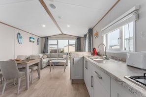 A modern kitchen with a built-in oven, a sink, and a window with blinds. - Chalet in De Haan With Terrace (De Haan)