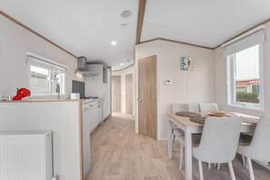 Una cucina moderna con mobili bianchi, un elettrodomestico rosso e un'area pranzo con tavolo e sedie.