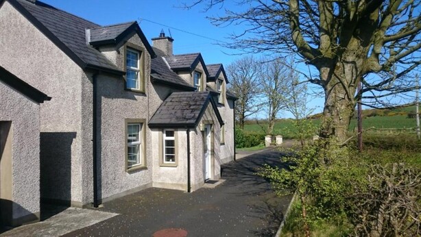 A traditional stone house with a steeply pitched roof, a small front porch, and a narrow driveway leading to the entrance. - Portrush Country Cottage with sea views. Perfectly situated for sightseeing. (Coleraine)