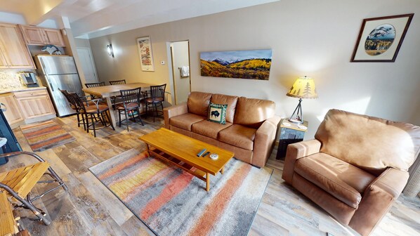 A living room with a brown leather sofa, a wooden coffee table, and a dining area with a wooden table and chairs. - Updated! Walk to Main St. Events, Dining, Shops. 1st Floor, Pool, Hot Tub (Frisco)