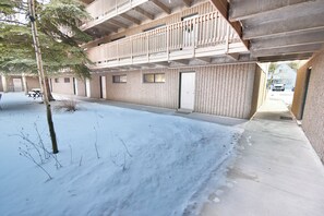 A multi-story building with a covered outdoor area, a snow-covered ground, and a visible door. - Updated! Walk to Main St. Events, Dining, Shops. 1st Floor, Pool, Hot Tub (Frisco)