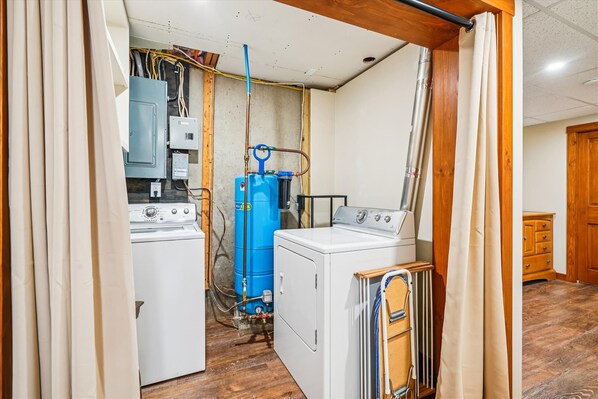 A laundry room with two washing machines, a blue water heater, and exposed electrical wiring. - 3 bedroom pet-friendly Killington retreat with fireplace and room for 8. (Killington)