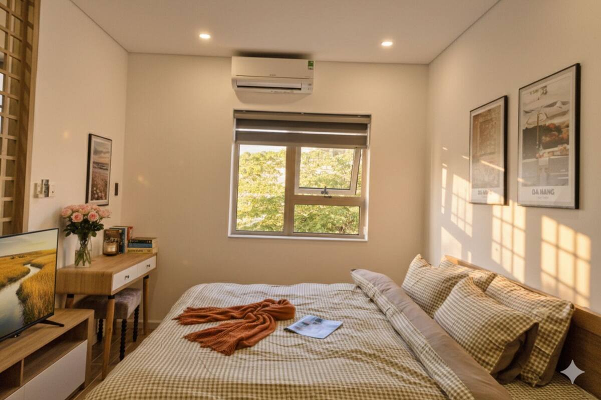 A bedroom with a bed, a desk, and a window.