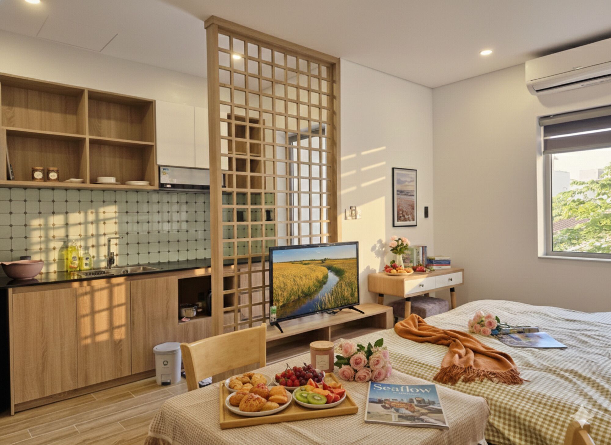 A modern room with a kitchen area, a dining table with food, a bed, and a window with a view.