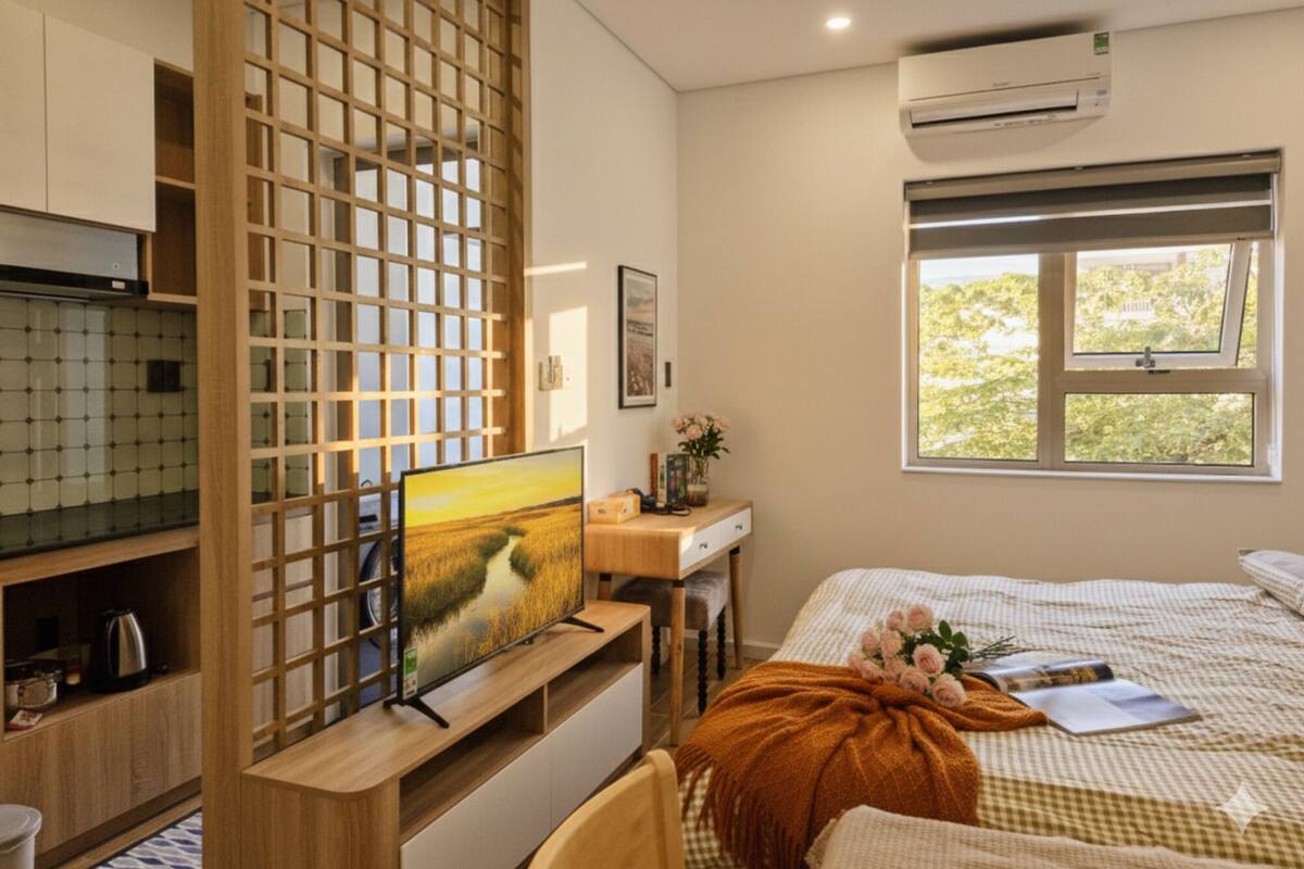 A modern bedroom with a bed, a desk, and a TV.