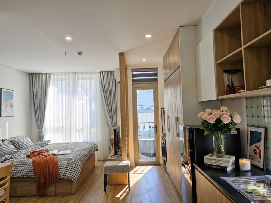 A modern bedroom with a bed, bedside table, and a view to the balcony.