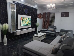 Una sala de estar moderna con un televisor de pantalla plana, un sofá, una mesa de centro y plantas decorativas.