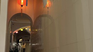 A corridor with tiled flooring, arched doorways, and hanging lanterns. - Golden Lotus (Hanoi)