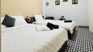 A hotel room with two beds, a patterned floor, and a wall with three framed pictures. - Golden Lotus (Hanoi)