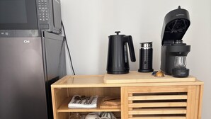 A kitchenette with a black refrigerator, a coffee maker, a kettle, and a microwave. - Innerbloom Stay Busselton - Guest House (West Busselton)