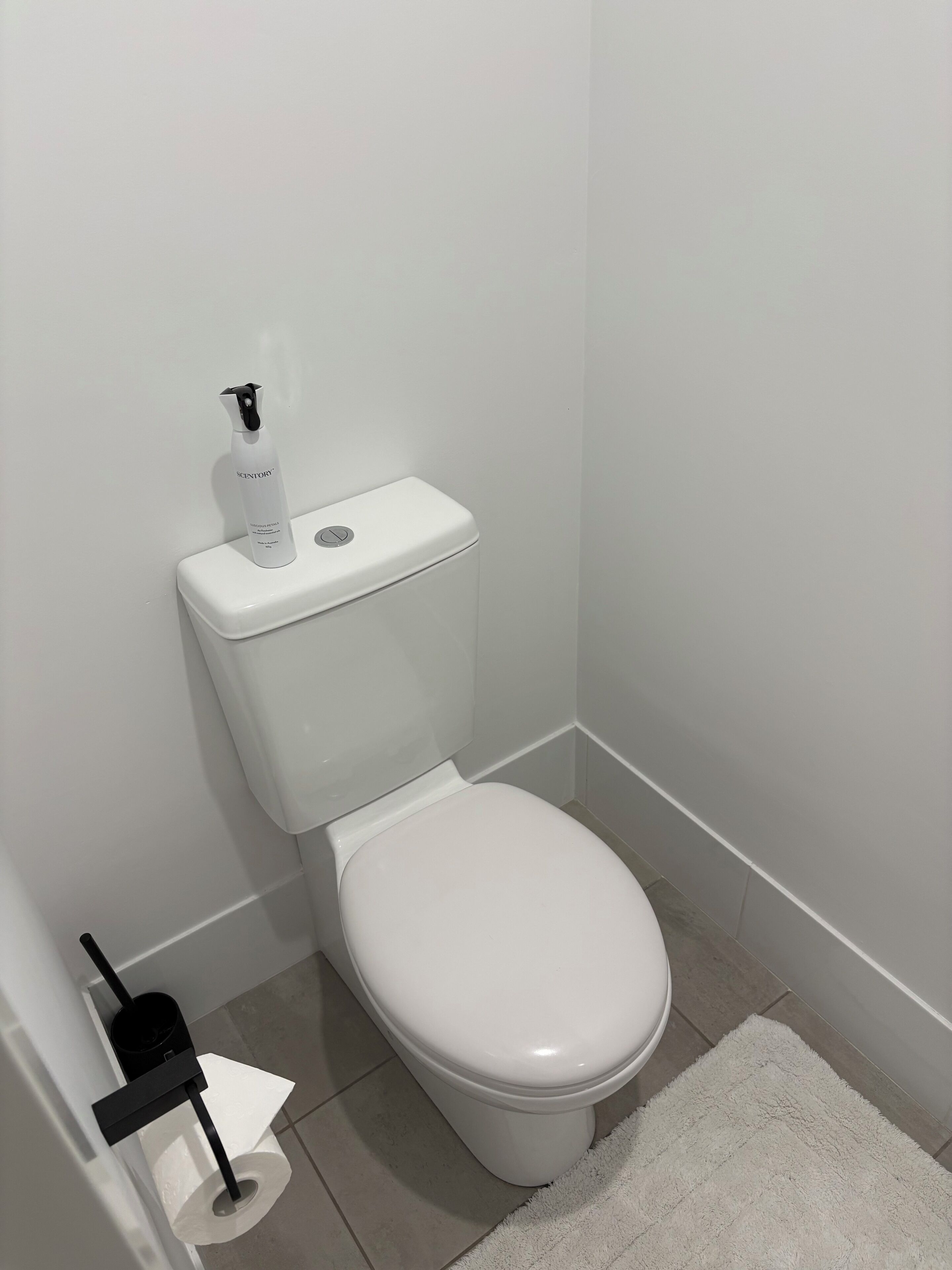 Eine weiße Toilette mit Bidetanschluss und Toilettenpapierhalter.