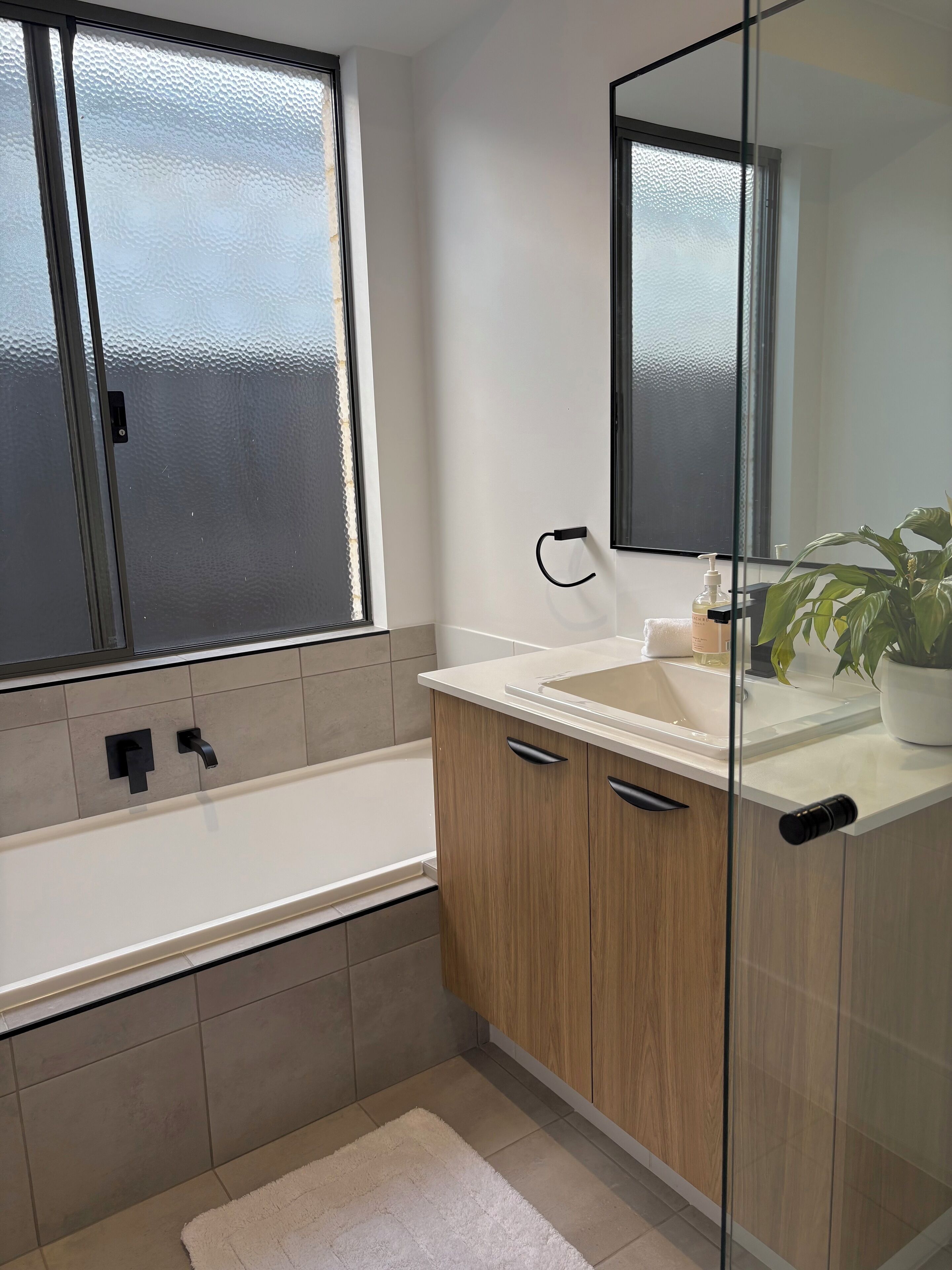 A modern bathroom with a bathtub, a sink, and a mirror.