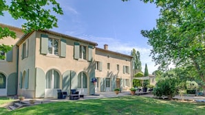 Ein zweistöckiges Gebäude mit Innenhof, ausgestattet mit einer Terrassenfläche, Möbeln und Kübelpflanzen.