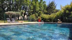 Ein klares Schwimmbecken mit Liegestühlen und einer Umzäunung.