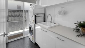 Una cocina moderna con lavadora integrada, un lavamanos y una ventana con vistas a una pared estampada.