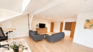 A spacious living area with a sofa set, a TV, and a wooden cabinet.